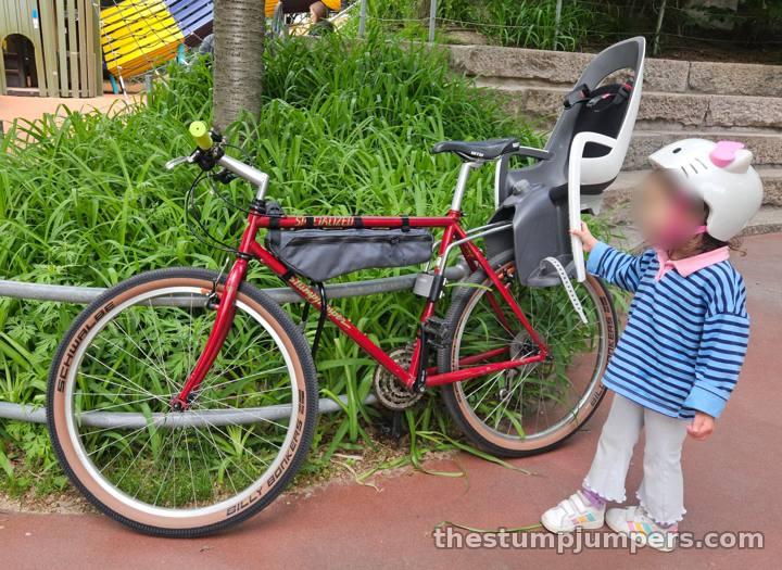 A red 1993 Specialized Stumpjumper bicycle with a child seat