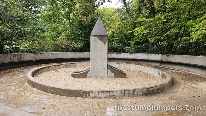 The toddler area: a sandpit and an awkward concrete slide thing under an obelisk.